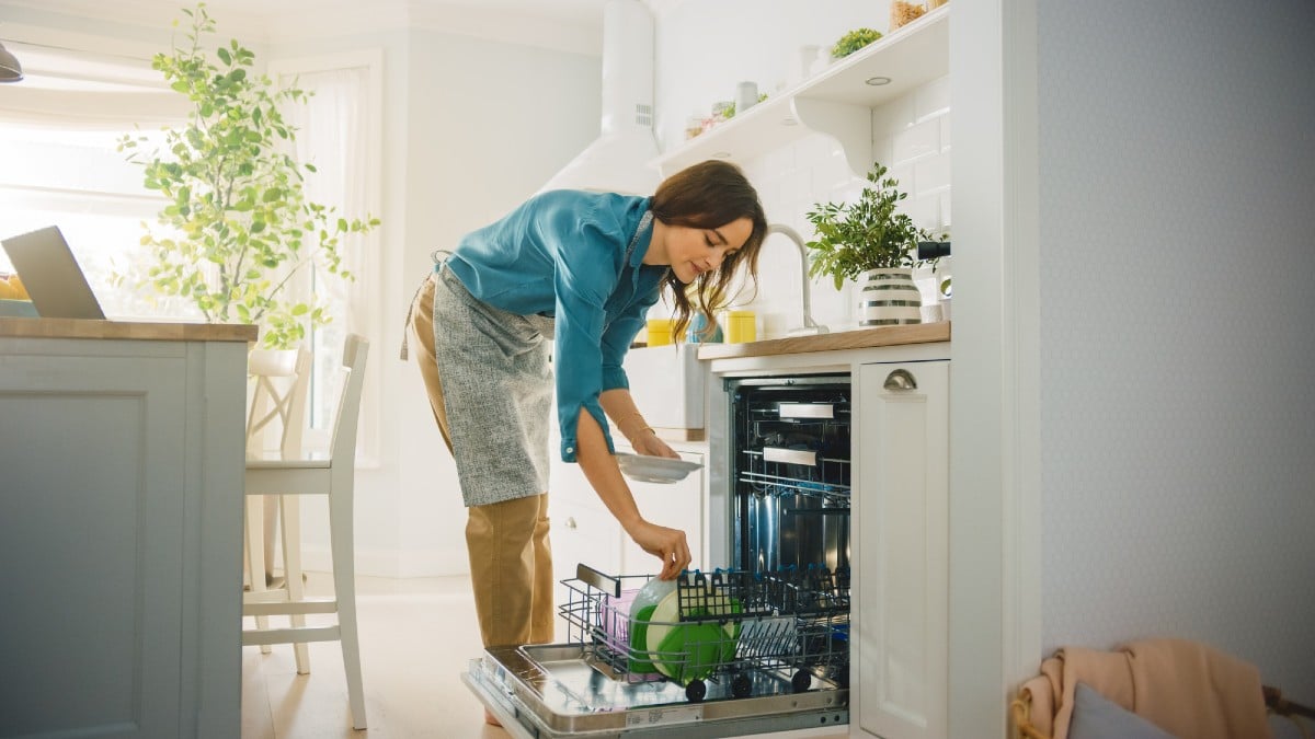 Female is Loading Dirty Plates into a Dishwasher Machine