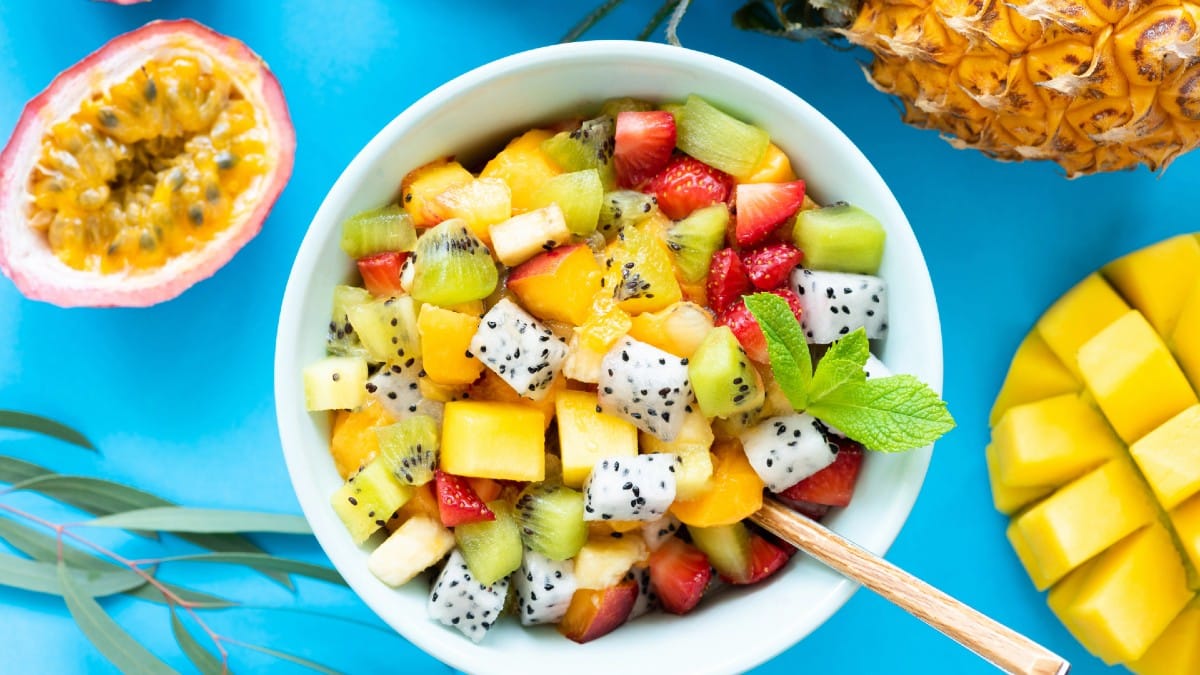 Fruit salad with tropical and exotic fruits on blue background