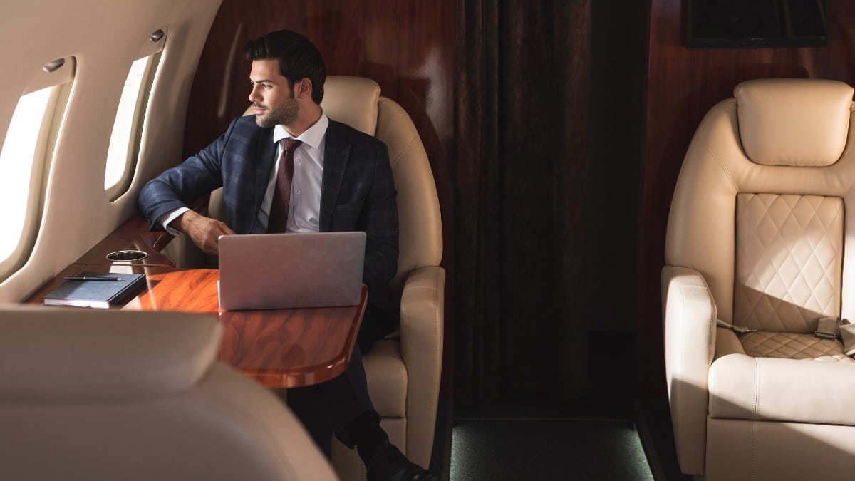 Handsome businessman working with laptop in his private Jet.