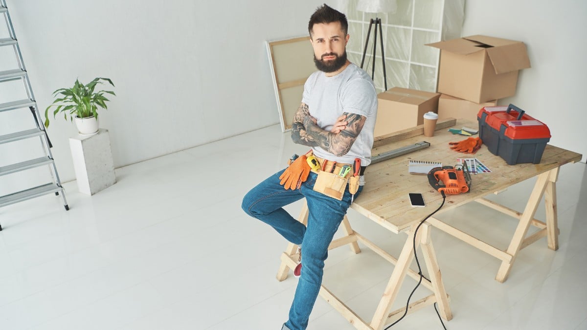 High angle view of handsome bearded tattooed man with tool belt 