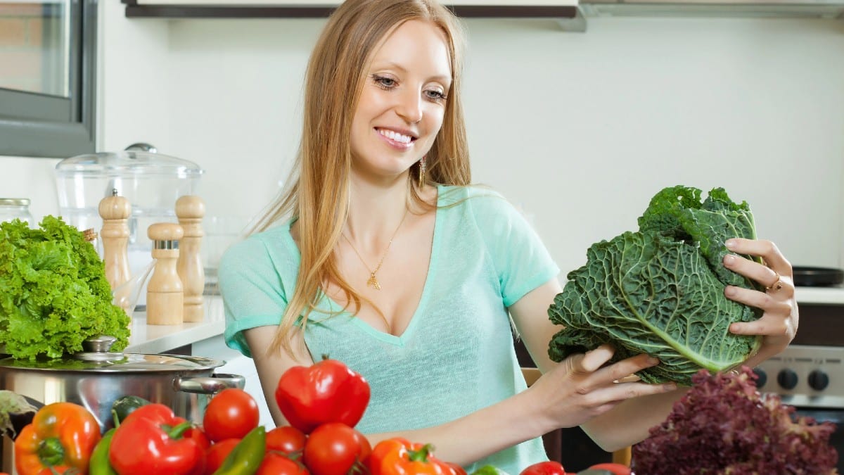 Housewife with raw cabbage and other vegetables
