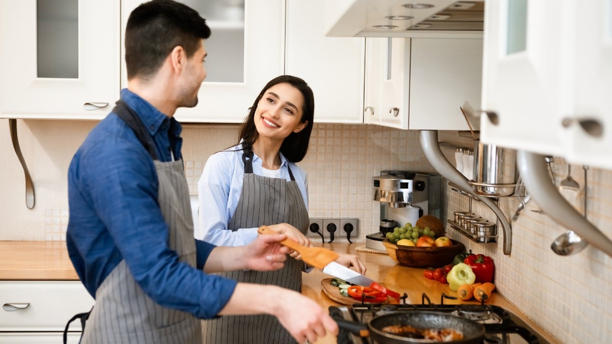 Loving couple preparing dinner frying on pan at home