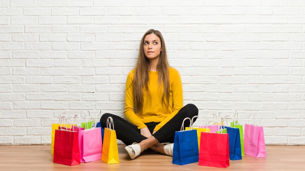 Young girl with lot of shopping bags with confuse face expression