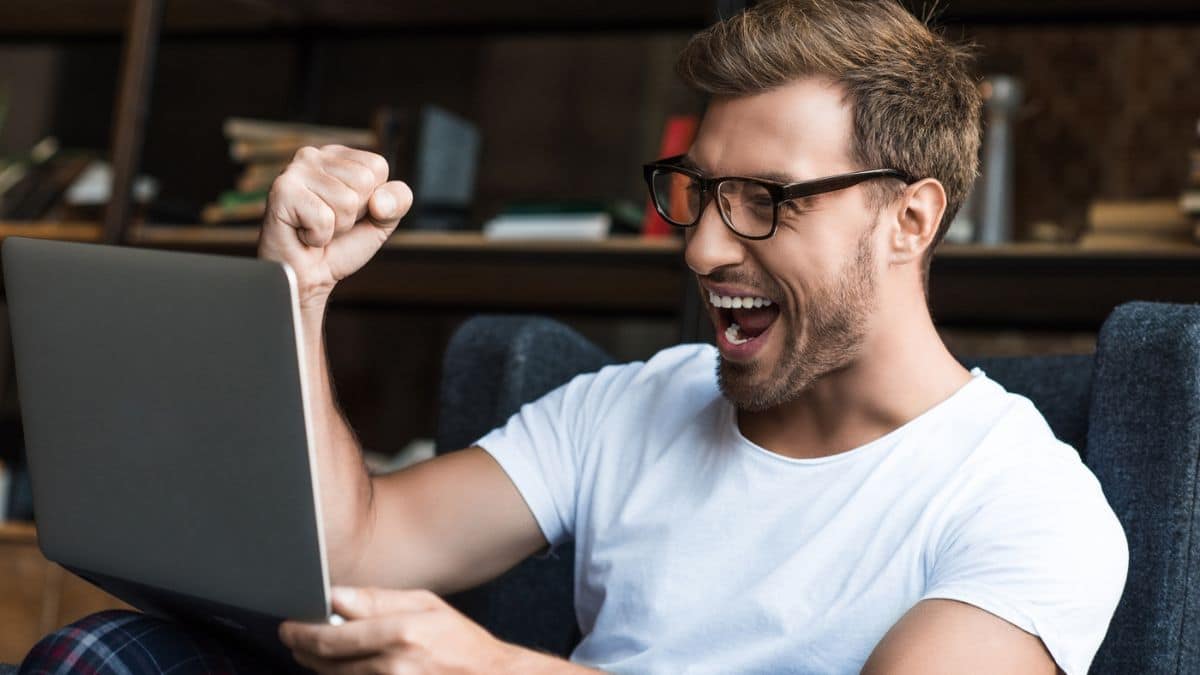 man glasses celebrating with laptop