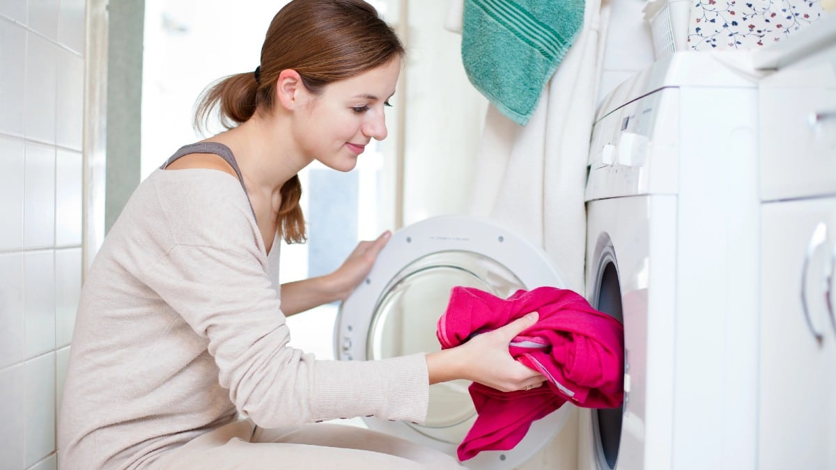 young woman doing laundry in washing Machine