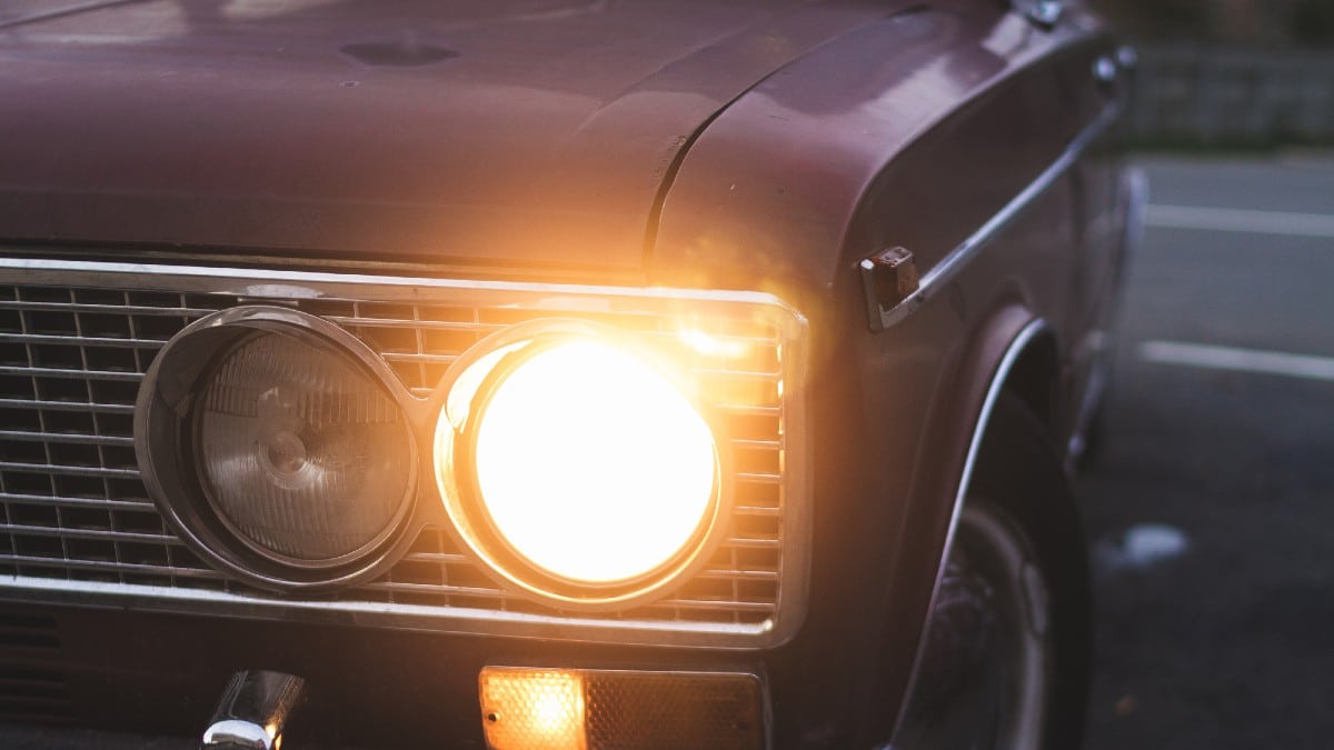 A closeup shot of the front of a car with a turned on light 
