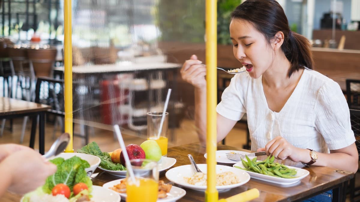 Asian woman sitting separated in restaurant eating food with table
