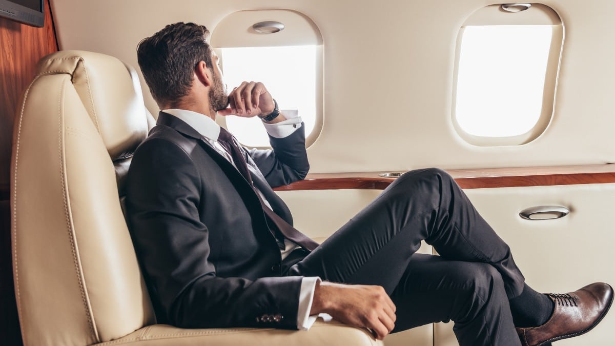 Back view of businessman in suit looking through window in private plane