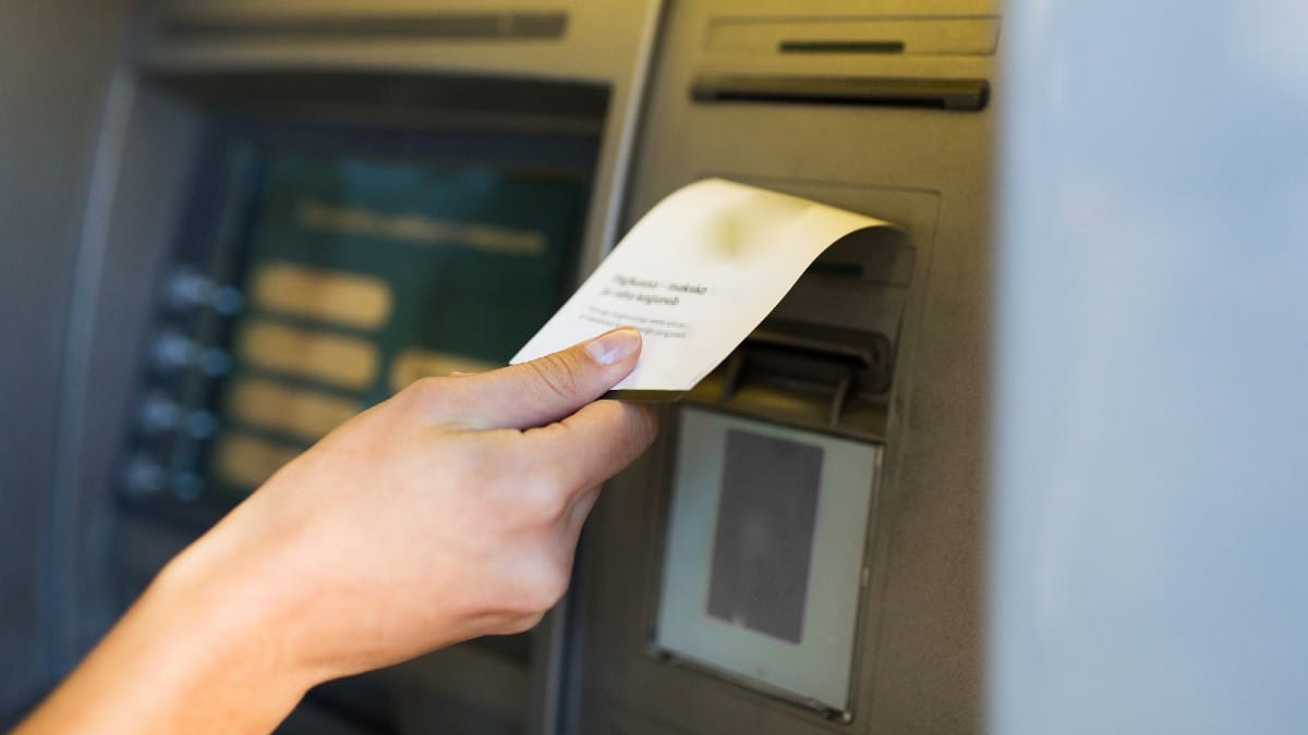 Close up of hand taking receipt from atm machine