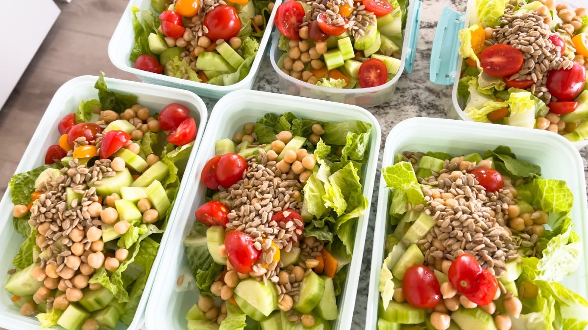 Containers filled with vibrant, nutritious salads are lined up on a kitchen