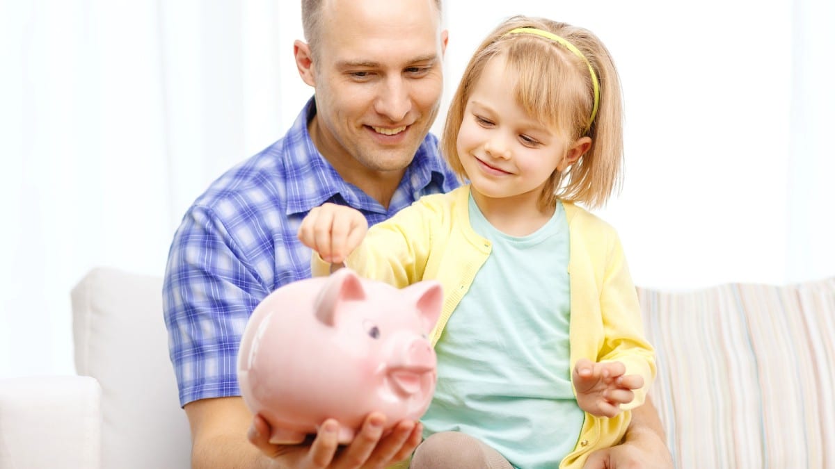Happy father and daughter with big piggy bank