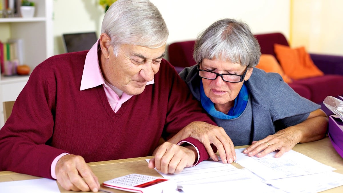 Happy senior couple at home calculating debt