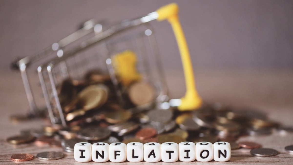 Inflation with coin and shopping cart on wooden background,