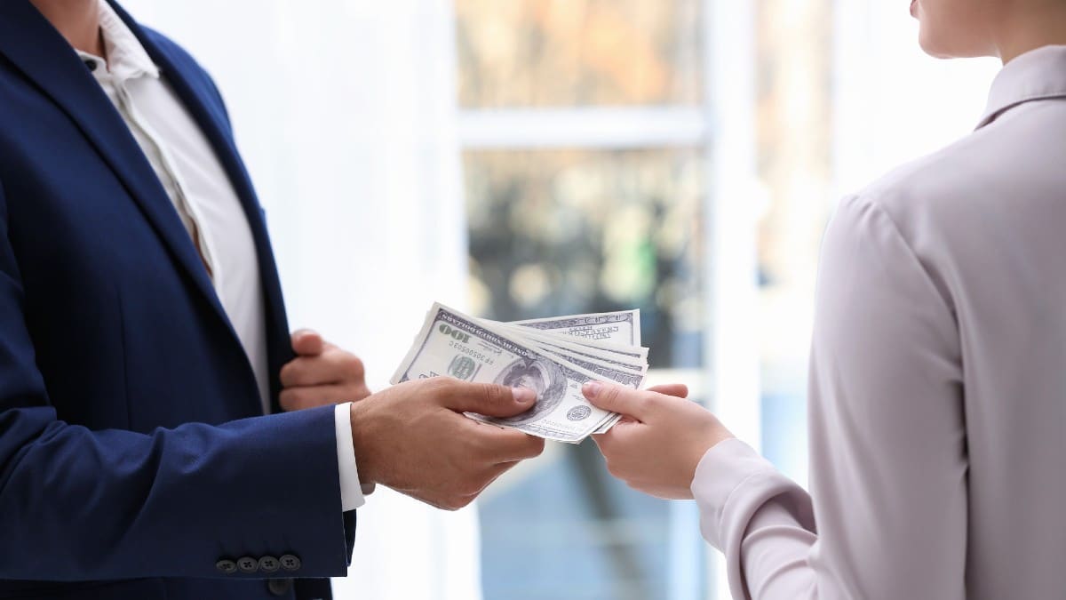 Man giving bribe money to woman indoors, closeup