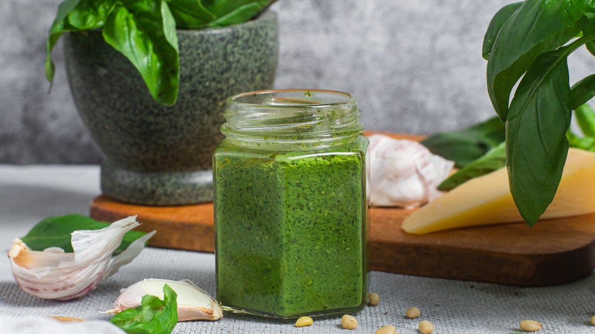 Pesto sauce in a glass jar on the table. Basil