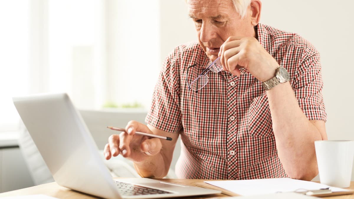 Portrait of modern senior man using laptop at home working
