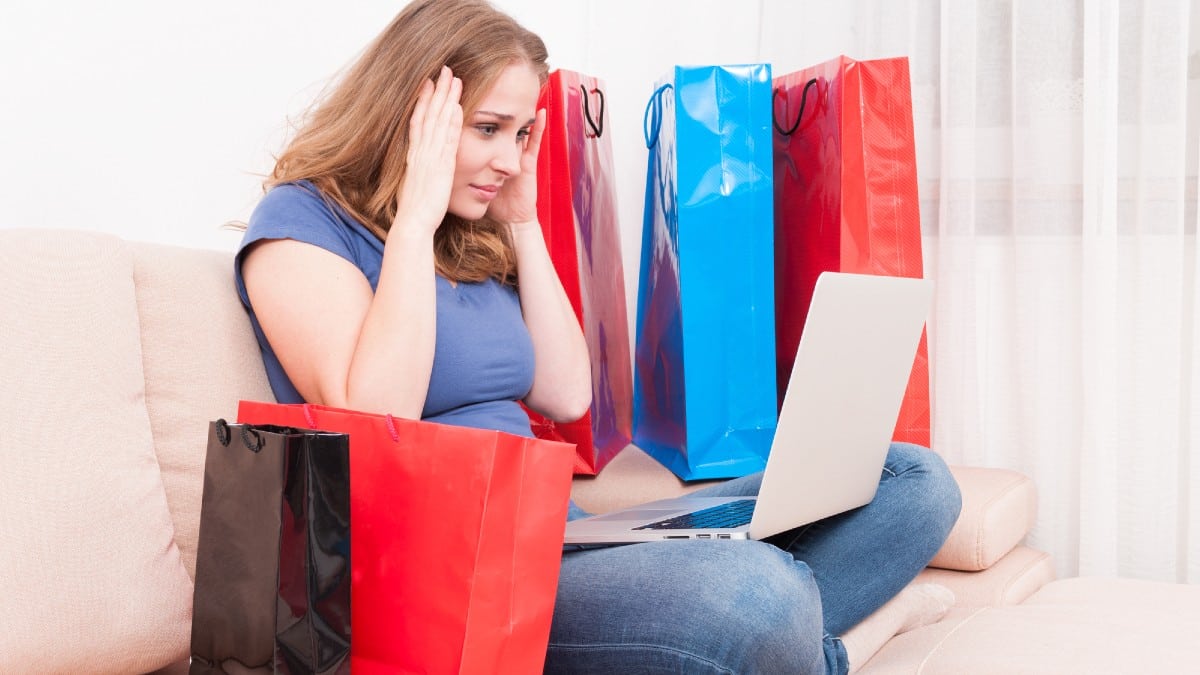 Shopaholic sitting on couch holding her head