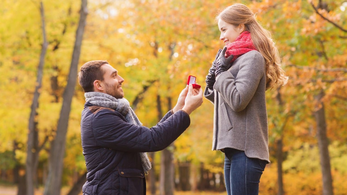Smiling couple with engagement ring in gift box 