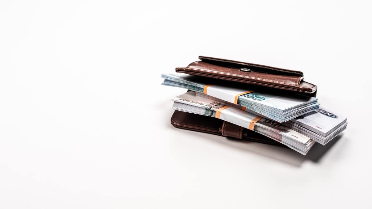 Stacks with russian money in leather wallet on white