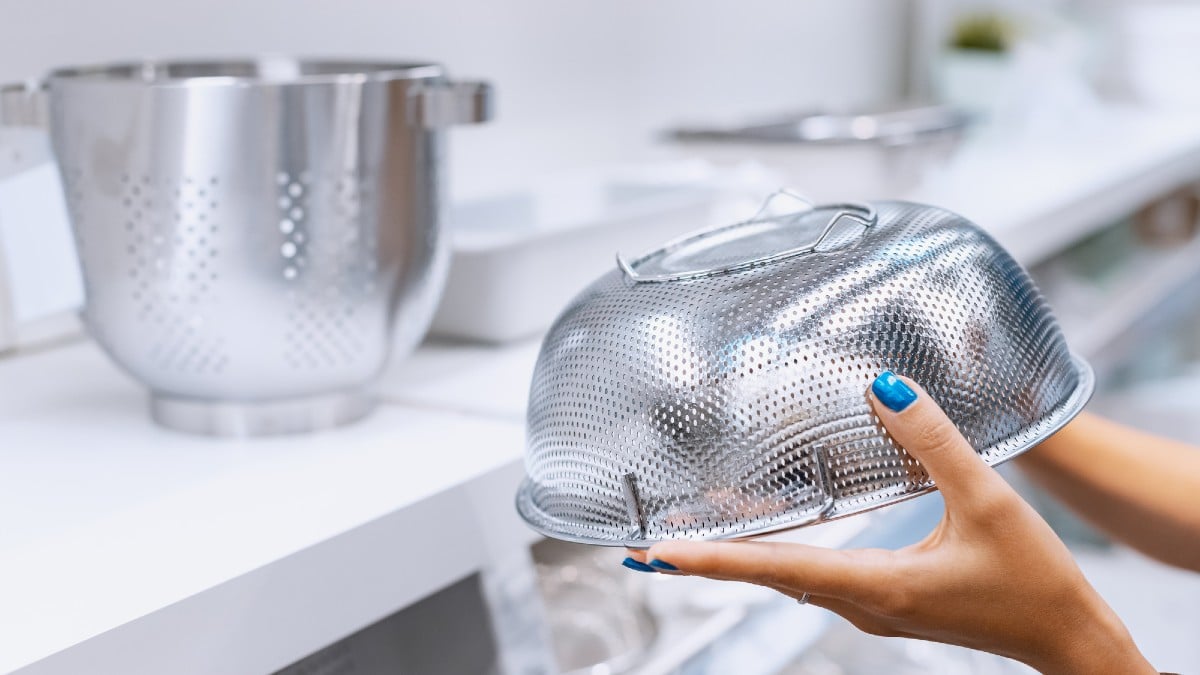 The housewife holds in her hands and chooses a metal colander