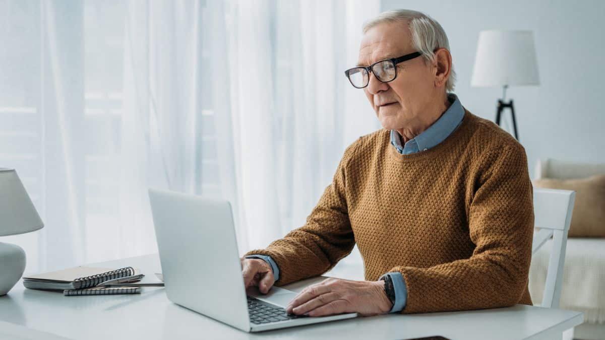 elder with glasses working on laptop