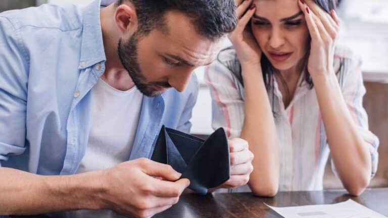 man and woman looking at empty wallet