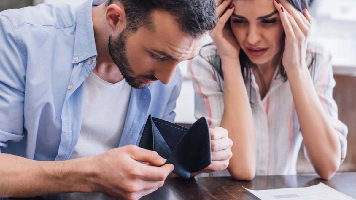 man and woman looking at empty wallet