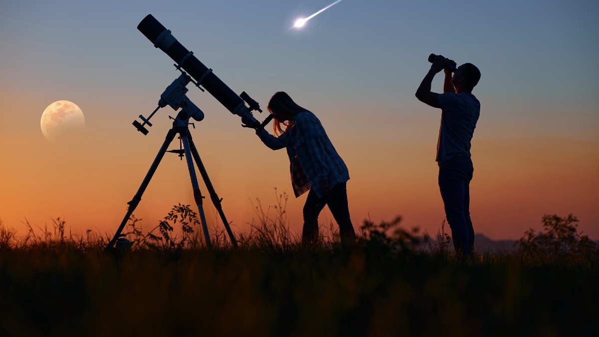 Couple stargazing together with a astronomical telescope
