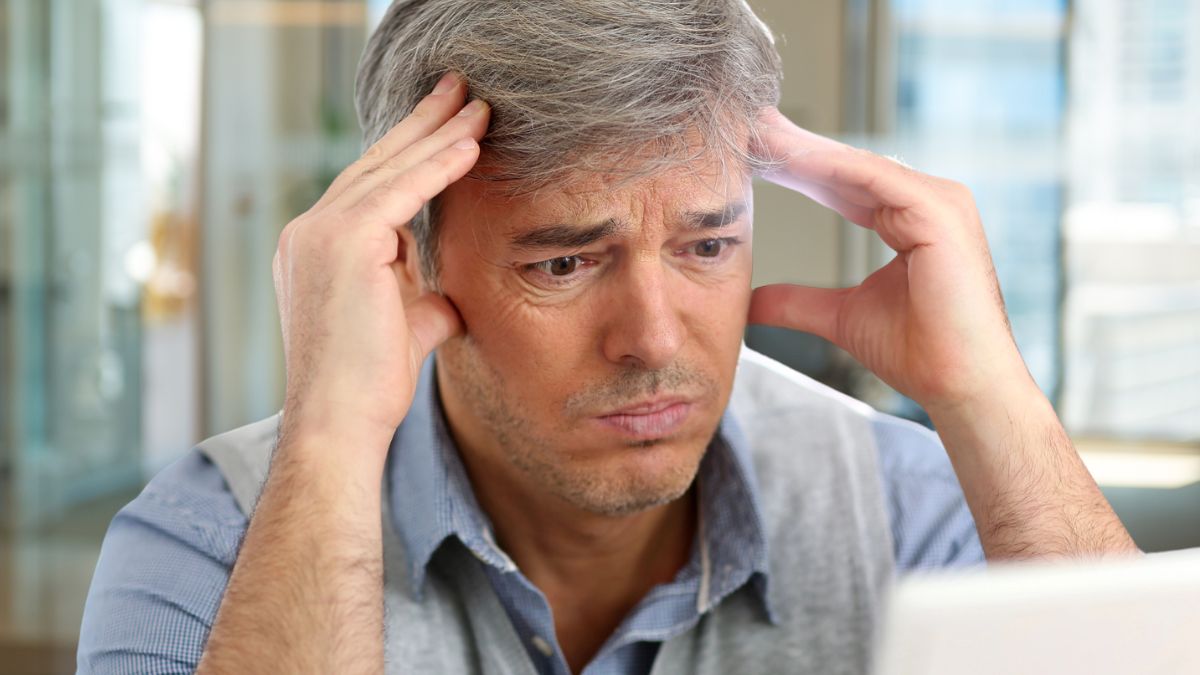 businessman with a headache in front of laptop
