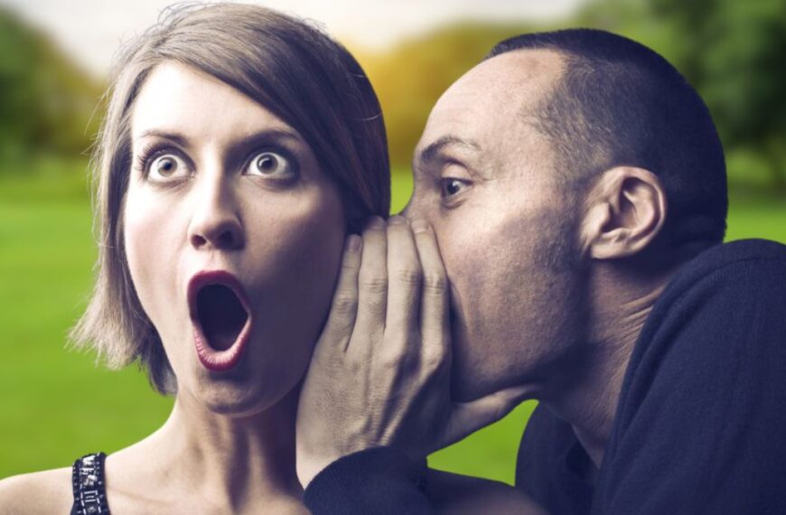 man whispering to a shocked woman