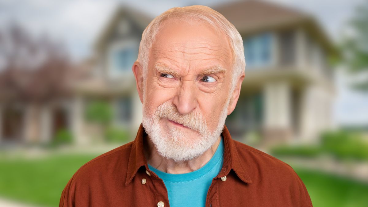 old man grumpy in front of house