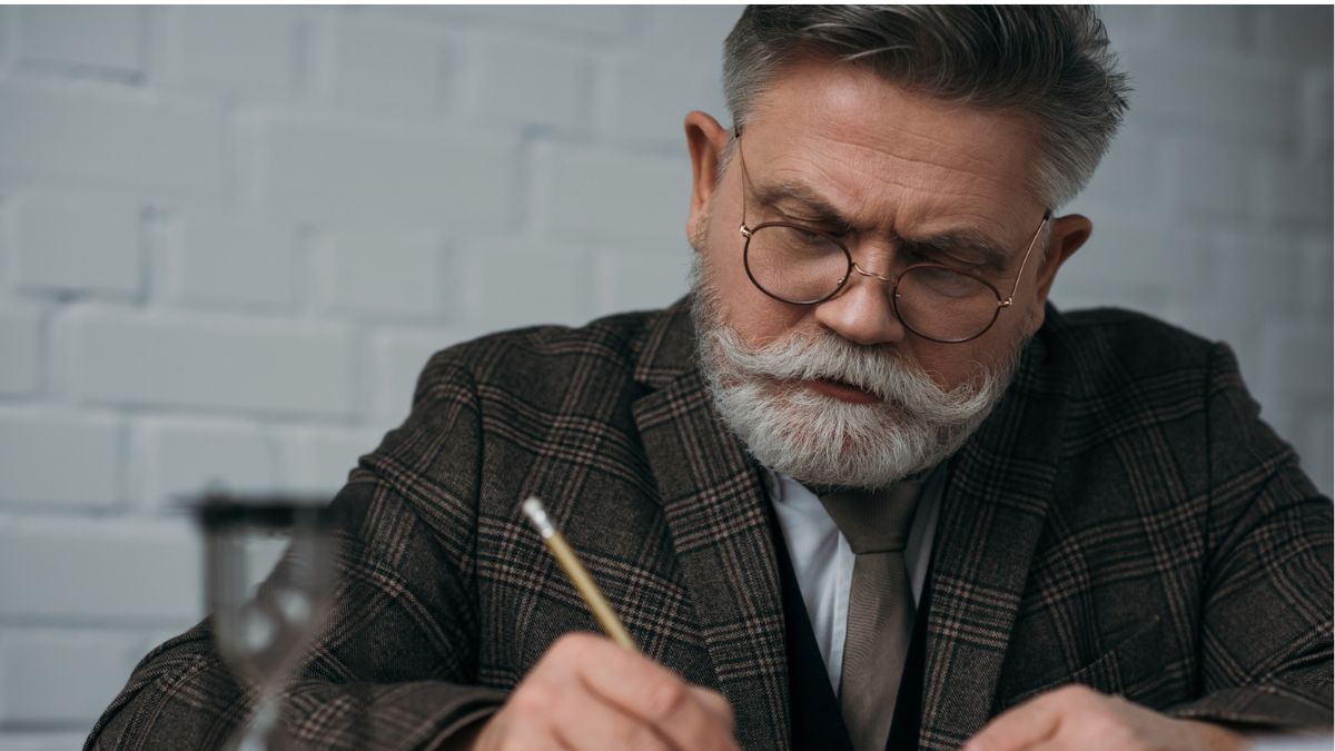 older man with mustache writing