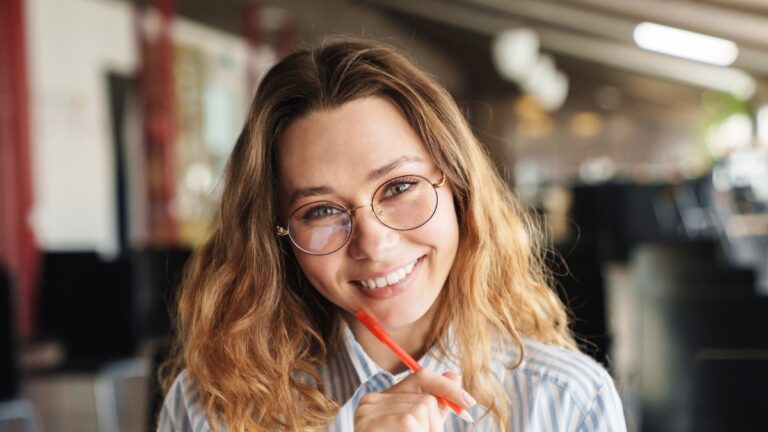 women in glasses holding pen in library